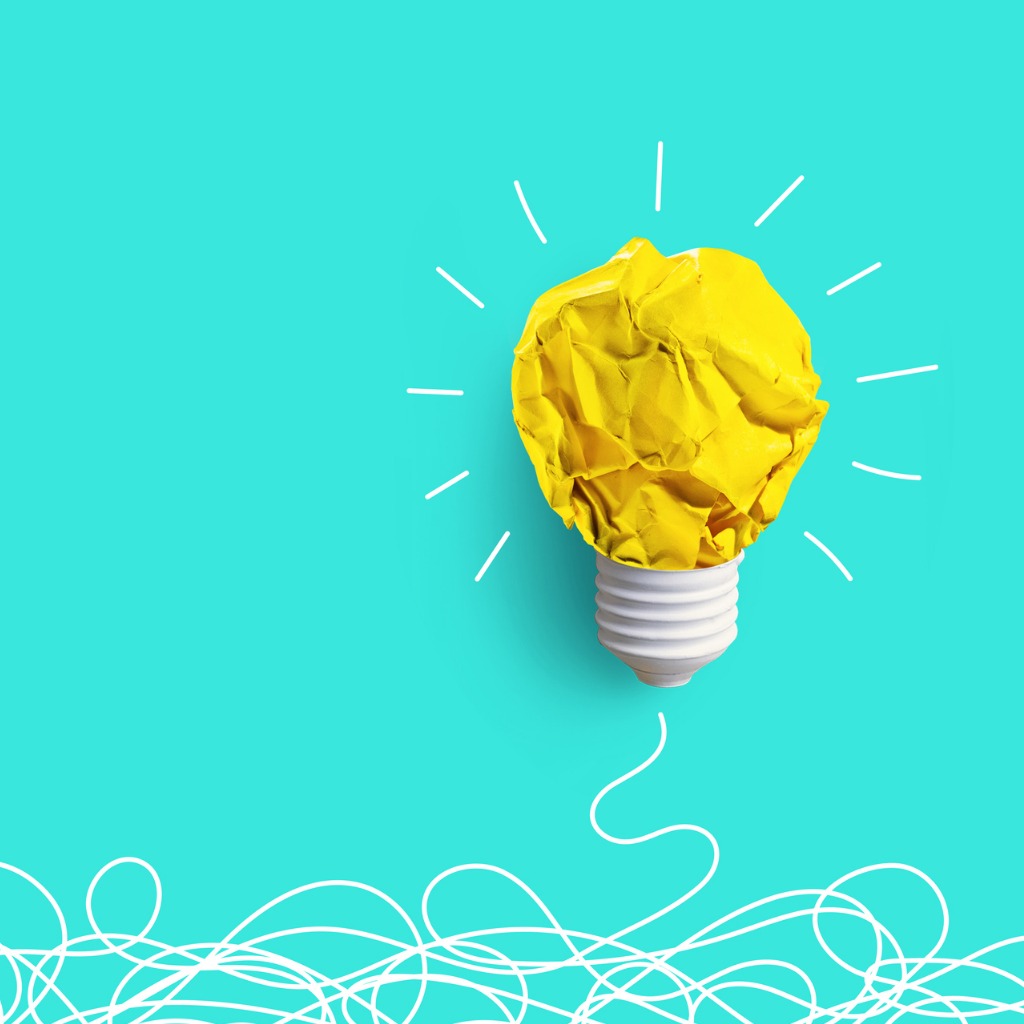 A crumpled yellow paper light bulb on a bright turquoise background